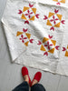 Quilt with star pattern on a white floor, person wearing red shoes partially visible
